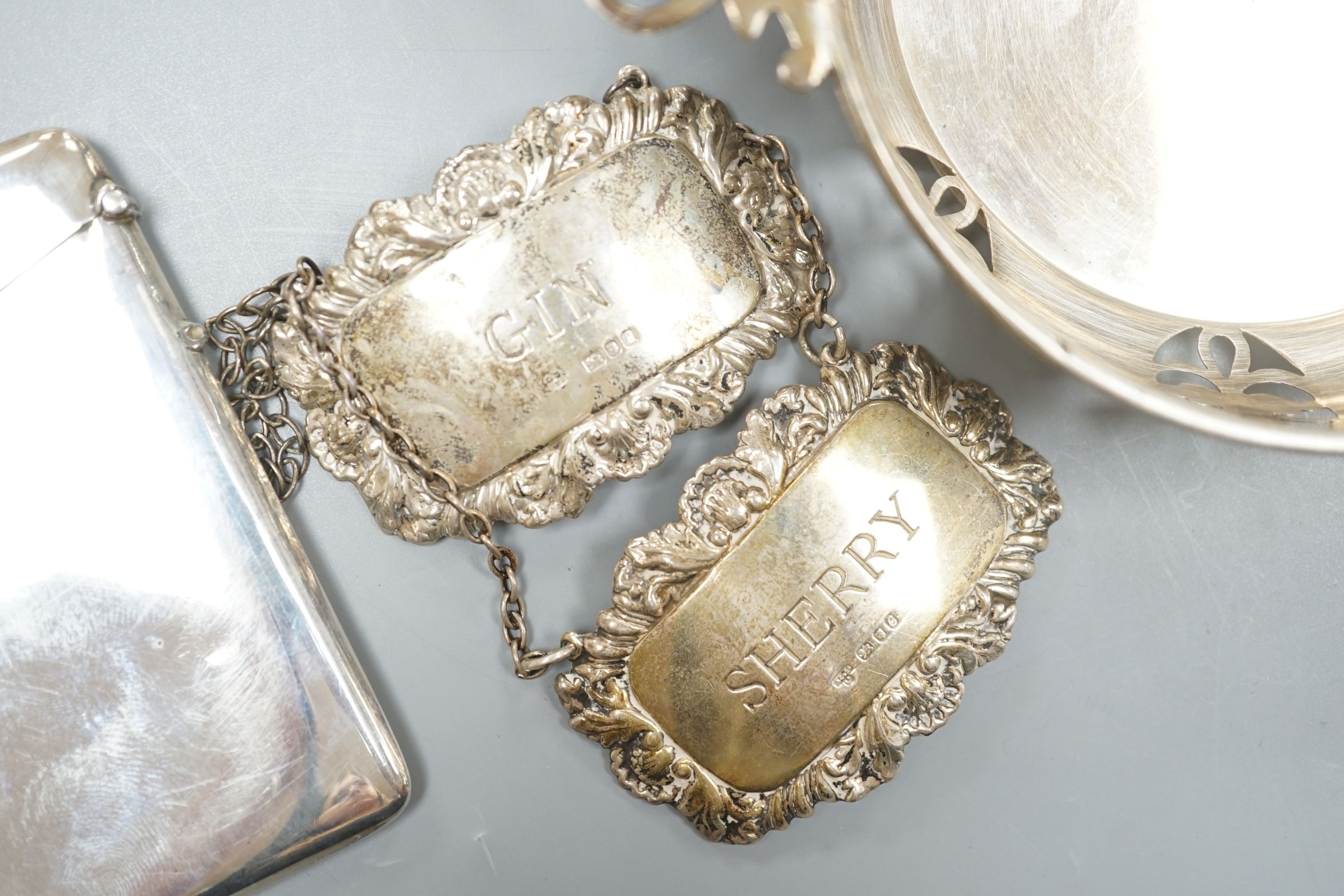 A circular sweetmeat with pierced sides and lug handles, Birmingham 1954, 10.75cm diameter, a plain rectangular card case, Birmingham 1914 and two modern silver wine labels, Gin & Sherry.
